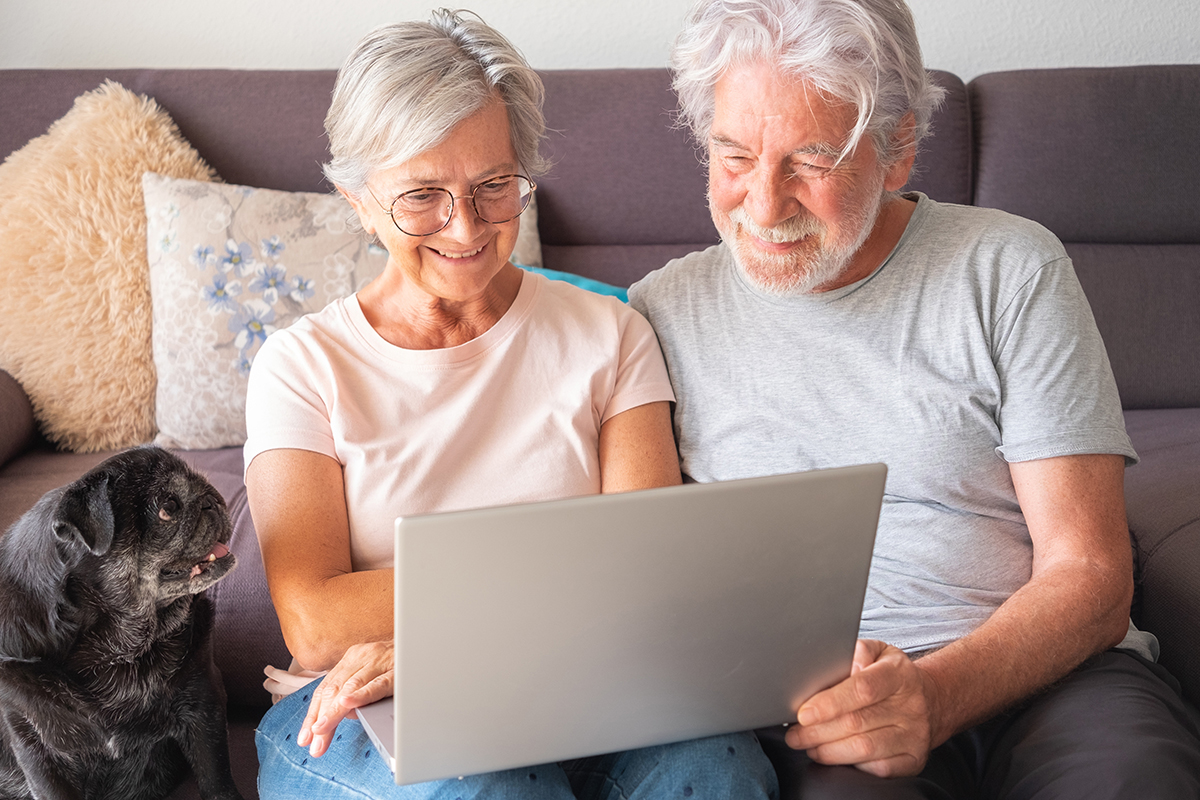 Elderly woman and man looking at a laptop on the couch