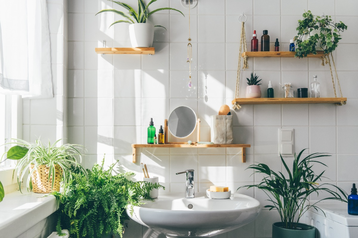 biophilic bathroom design with white tile, wooden accents, and greenery